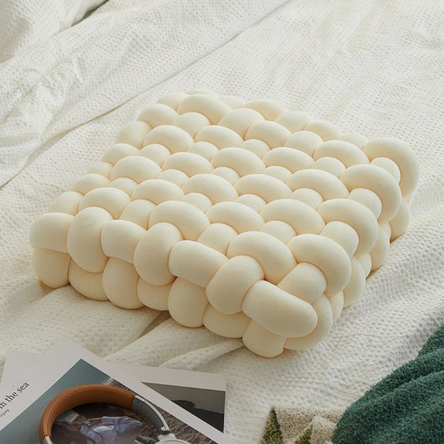 Elyisia comfort kussen met een verfrissend en elegant ontwerp, geplaatst op een bed. Het kussen heeft een zachte, gevlochten structuur die zorgt voor comfort en ondersteuning. Perfect als decoratief accent of zitkussen voor extra ontspanning in huis.