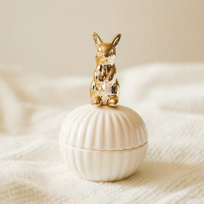 Een elegante opbergpot in de vorm van een schelp, met een gouden konijn als deksel. Het verfijnde ontwerp van het konijn en de pot geeft een speelse en chique uitstraling aan elke ruimte.